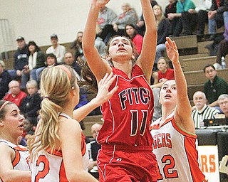 Austintown Fitch’s Megan Sefcik (11) goes up for two between Howland’s Gabby Cvengros (22) and Jordan
Entler (12). Sefcik scored her 1,000th point Thursday at Howland.