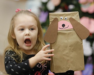 Gianna Page, 3, of Poland shows off the puppet dog she made at the Poland Branch of the Public Library of Youngstown and Mahoning County. She was taking part in the “Baby Brilliant: Tales and Talk for 2s and 3s” program at the library. At top, Vikki Peck, children’s librarian, reads a story while below, Emily Swantek, 3, and her baby sitter, Jyl Willoughby, pay attention during the program.
