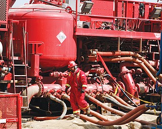 An unidentified worker steps through the maze of hoses being used at a remote fracking site being run by Halliburton for natural-gas producer Williams in Rulison, Colo. The oil and gas industry is trying to ease environmental concerns by developing nontoxic fluids for the drilling process known as fracking.