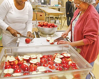 Shauna Spencer, left, and Mary Flores wash, cut and prepare thousands of apples for elementary school students’ lunches at the Youngstown City Schools’ central kitchen at Choffi n Career and Technical Center. The district bought the apples, which were grown in Greenford through the Lake-to-River Food Cooperative with the help of a grant.
