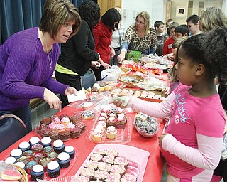 Poland North Elementary second-grader Arikia Chism makes a purchase from Melissa Kellgren, a member of the parent-teacher organization, during a bake sale Tuesday. The event benefited the Diaz family of Poland, whose 7-month-old son, Jackson, was born with a rare congenital disorder.