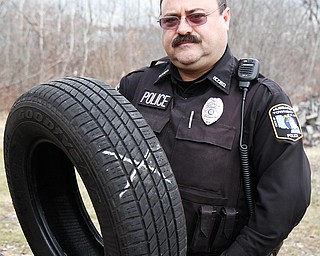Officer William Greene of the Hubbard Township Police Department shows a tire that was recovered from a rural
township road. The police have seen an influx of old tires being illegally dumped on rural roads.