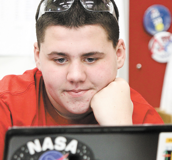 Freshman Aaron Scott checks his computer while working with the robotics team’s new robot. Every year, For the Inspiration and Recognition of Science and Technology (FIRST), the governing body behind the robotics competitions, requires new standards for the nation’s high school teams.