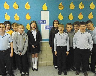 Fourth-grade students of Holy Family School are standing in front of the Lumen Christi bulletin board. They are, from left in front, Steven Hiner, Caitlin Palusak, Jacob Shogren and Patrick Assion; and, in back, Dominic DeToro, Patrick Howlett, Ava Szalay, Augusta Fox, Payton McMahon, Brian White and Matthew Ranno. The board was designed by fourth-grade teacher Kathy Holsinger to make students and families aware of Catholic identity and faith infused with learning. The new Lumen Christi Catholic School System includes Catholic elementary schools in the Mahoning Valley. In Latin, the name means Light of Christ and is put into practice through daily prayer, regular liturgy participation and the compassion students demonstrate through varied service projects.