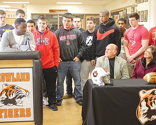 Longtime Mahoning Valley football coach Dick Angle, seated, announced his retirement Thursday at Howland High School. Michigan recruit De’Veon Smith, at podium, and other players saluted the Tigers’ 15-year head coach.