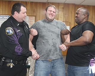 Hubbard Township Officer Justin Rydarowicz reacts to being shocked with a stun gun as fellow Officer Ken Steepleton, left, and Youngstown Officer Carlo Eggleston assist during police training Thursday night in Hubbard.