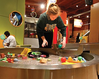 Danielle Buseth, a freshman at North Dakota State University, spruced up the “River of Knowledge” display at OH WOW! The Roger & Gloria Jones Children’s Center for Science & Technology in Youngstown on Monday. Buseth was part of a group of 30 students traveling to Washington, D.C., and doing community-service projects along the way.