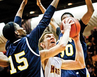 Cardinal Mooney’s Doug Caputo (42) tries to shoot as he is hemmed in by Warrensville Heights defenders Jermaine Brown (15) and Trevon McGhee (30) during the Division II regional semifinal Thursday at Canton Memorial Fieldhouse. The Cardinals’ season came to an end at the hands of the Tigers, who won 69-61.