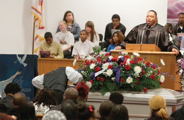 A mourner kisses the coffin of Daylan T. Ray, 15, after it was closed Monday as the Rev. Phillip Shealey of Greater Apostolic Faith Church in Warren delivers the eulogy. Daylan was one of six teens killed in a rollover SUV crash. The Rev. Mr. Shealey said parents have to be more vigilant as children grow.