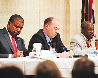 Youngstown Democratic mayoral candidates Jamael Tito Brown, left, and John McNally IV take notes as Matthew Smith speaks during their first debate Thursday night at Fellows Riverside Gardens’ D.D. and Velma Davis Education & Visitor Center at Mill Creek MetroParks.