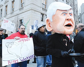 Protesters, including one costumed as Gov. Rick Snyder, stand outside the Detroit Athletic Club in Detroit on Thursday. Unionized workers and others protested outside the club as Snyder addressed a “Pancakes & Politics” breakfast. The protesters demonstrated against the right-to-work law that took effect Thursday that allows workers to decide not to pay dues to a union as a condition of employment.