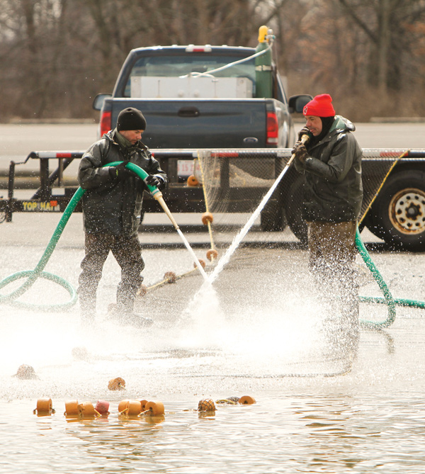 Ohio Department of Natural Resources workers Matt Wolfe, left, and Steve Moss didn’t have too much fun in the cold Monday cleaning nets used this weekend to catch walleye eggs for hatching. Last month was colder with more snow than a typical March for the area, and the start of April wasn’t any better.