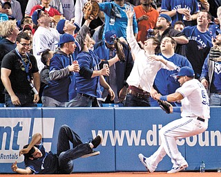 A fan falls onto the field as Toronto Blue Jays left fielder Melky Cabrera chases a foul ball during the fourth inning of the season opener against the Cleveland Indians on Tuesday in Toronto. The Indians won 4-1.