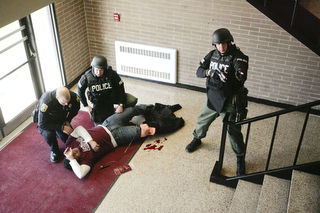            ROBERT K. YOSAY  | THE VINDICATOR..Tending to an injured student (Braxton Menendez a junior at BHS )- Ptl Paul Poulis and Sgt Mike Huges  - as Sgt Glen Riddle watches the staircaseBPD and area law enforcement had a mock drill of a shooter at Boardman High School - .. - -30-..