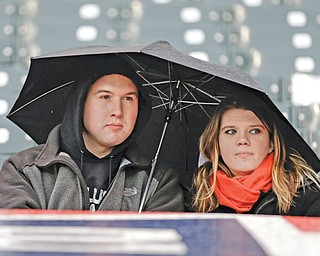 Fans sit under an umbrella in the rain at Progressive Field in Cleveland before the start of Thursday’s baseball game between the Indians and Yankees Cleveland. The teams were rained out for the second night in a row.