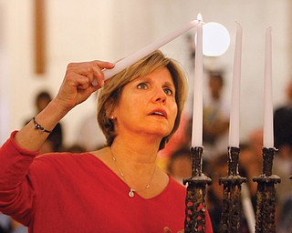Terri Anderson of Youngstown, a child of survivors of the Holocaust, lights the first candle during a ceremony at the 20th annual Yom Hashoah (Holocaust remembrance) on Thursday at the Mahoning County Courthouse. The theme was “Never Again: Heeding the Warning Signs.”