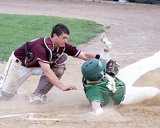 Harry Finelli of Ursuline slides into home plate to score ahead of the tag by South Range catcher Mitch Dolak during the fourth inning of their baseball game Thursday at Cene Park in Struthers. The Irish downed the
Raiders, 18-3, behind pitcher Sam Donko, who allowed only one run, scattered three hits and struck out nine in
his four innings on the mound.