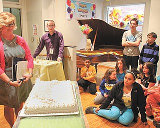 Becky Keck, director of Youngstown State University’s SMARTS — Students Motivated by the Arts — and a groups of SMARTS students gather around a cake Thursday to celebrate the program’s 15th anniversary.