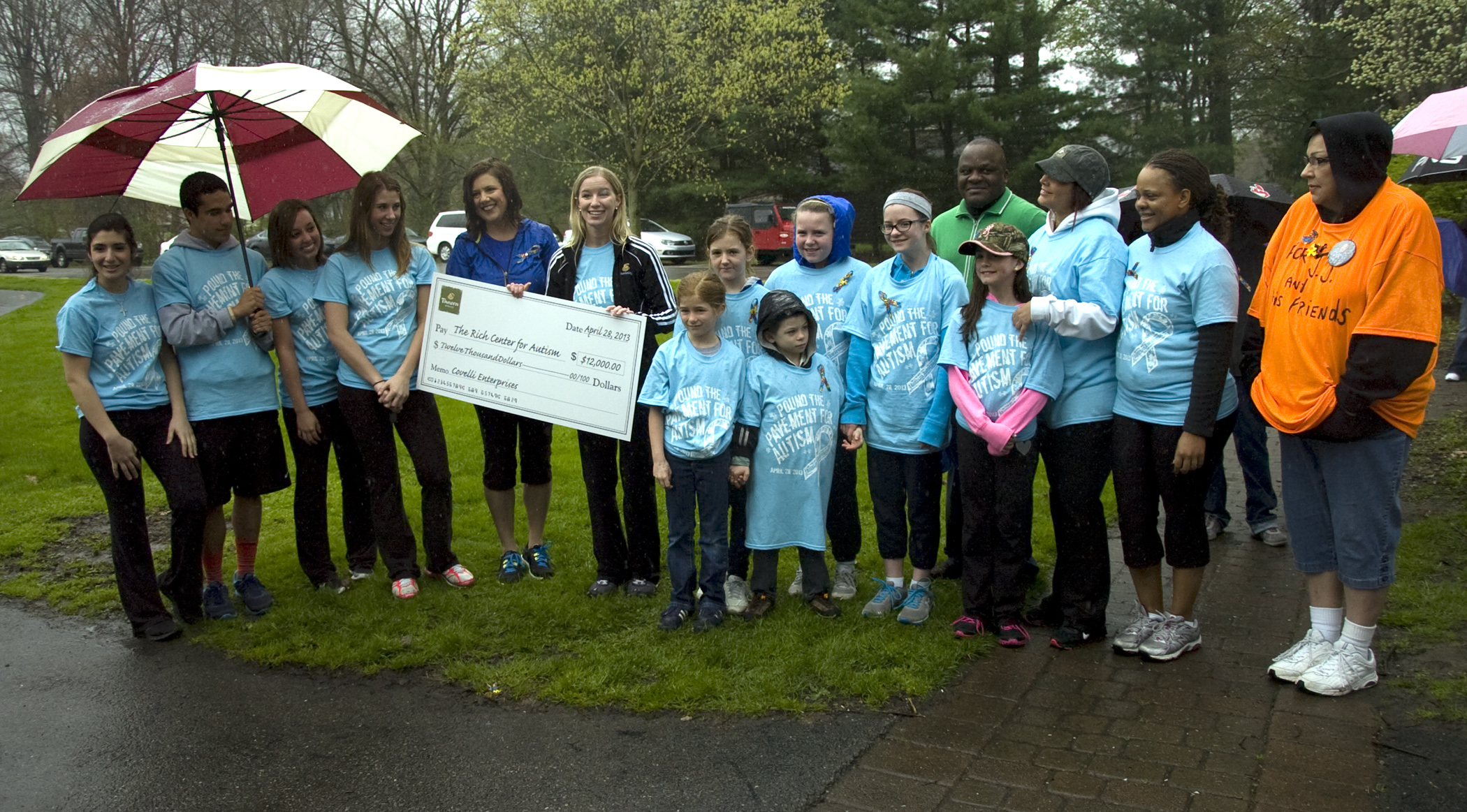 Kelli Cardinal/The Vindicator
Leah Wilson (center, left) of the Rich Center for Autism, and Liz Follet, of Covelli Enterprizes, hold the $12,000 check Sunday during a presentation before the Pound the Pavement for Autism walk in Howland Township Park.