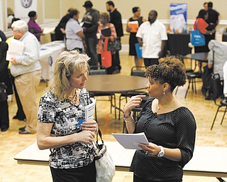Donna Van Natten with The Enterprise Center, left, and Valoria Armstrong with Tennessee American Water Co. converse during a job fair Tuesday at the Urban League in Chattanooga, Tenn. The Labor Department reported Thursday that the number of Americans applying for unemployment aid fell last week to a seasonally adjusted 324,000 — the fewest since January 2008.