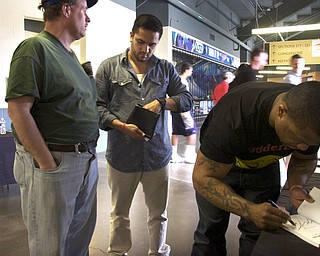 Kelli Cardinal/The Vindicator
Maurice Clarett (right) a former Ohio State running back, autographs a copy of his book Saturday for Scott Eynon (left) of Youngstown, who was speaking with Nate Ortiz (center) a youth pastor at Victory Christian Center, at the Men's Rally in the Valley at the Covelli Center in Youngstown. Clarett and Ortiz were working to promote and help raise money for The Comback Project.