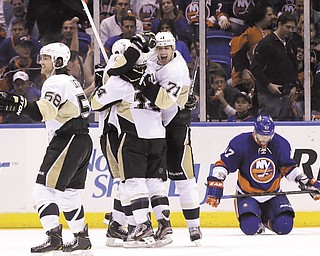 A dejected Andrew McDonald of the New York Islanders hangs his head while Pittsburgh’s Chris Kunitz (14), Kris Letang (58) and Evgeni Malkin (71) celebrate the Penguins’ win in Game 3 of the Stanley Cup Playoffs
Eastern Conference quarterfinals Sunday at Nassau Veterans Memorial Coliseum in Uniondale, N.Y. Kunitz scored the winning goal in overtime to lift the Penguins over the Islanders 5-4 and give them a 2-1 lead in the series.