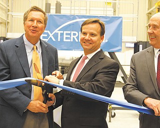 Ohio Gov. John Kasich, left, helps Brad Childers, Exterran chief executive officer, cut a ribbon at the company’s new plant on Salt Springs Road. At right is Tom Humphries, head of the Youngstown/Warren Regional Chamber.