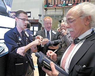 Specialist Bradley Kessler, left, works with traders on the floor of the New York Stock Exchange on Tuesday. The Dow Jones industrial average punched through another milestone Tuesday: its first close above 15,000.