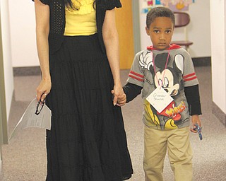 Sheila Palombo, who will be a kindergarten teacher at the new Austintown Elementary School, walks future kindergartner Quander Shouse through stations at kindergarten registration Thursday.