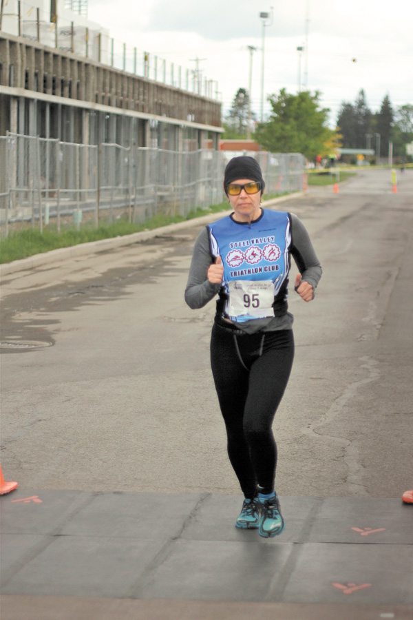 Kathleen Dearing of Poland crosses the finish line after running a 5K to finish off Sunday’s triathlon at the YMCA in Boardman.