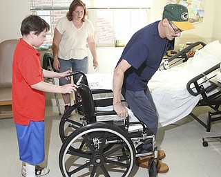William D. Lewis\The Vindicator Russell Marshall of Berlin Center gets into his wheelchair as son Jacob, 11, and wife Melissa Marshall look on at Canterbury Villa in Alliance where Marshall is undergoing rehabilitation after a March farming accident..He lost his arm and suffered horrific injuries in the accident.