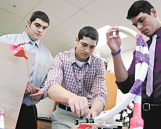 From left, Girard High School seniors Brandon Martuccio, Frank Rich and Alessandro Baschieri display their project, the Rube Goldberg, in their physics class that will be counted as college credit through Youngstown State University’s College in High School program.