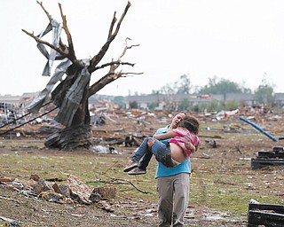 A woman carries her child through a field near the collapsed Plaza Towers Elementary School in Moore, Okla., after a monstrous tornado at least a half-mile wide roared through the Oklahoma City suburbs Monday.