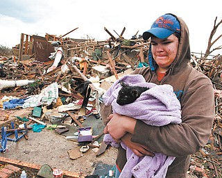 Austin Brock holds her cat, Tutti, after the animal was retrieved Tuesday from the rubble of Brock’s home. The home was demolished Monday when a tornado moved through Moore, Okla.
