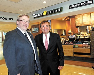 Rick Hodges, left, executive director of the Ohio Turnpike Commission, and Sam Covelli, right, owner/operator of Covelli Enterprises, stand in front of one of Covelli’s Panera Bread cafes in the new Glacier Hills Service Plaza on the Ohio Turnpike in Springfield Township.