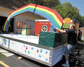 Duane Ward, a member of Westminster Presbyterian Church in Boardman, puts a rainbow in place on a float for Serendipity Christian Preschool at the church. Larry Hoff man is obscured by the rainbow.