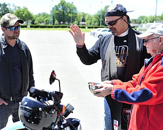 Reverend Jeff Baker (center) blesses the Harley Roadster of Jeremy Redmond (left) of Brookfield. Richard Bess (right) of Howland holds a bowl of holy water for the blessing. 