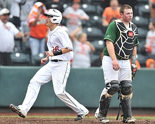 Wheelersburg baserunner #26 Wade Martin crosses home plate behind Ursuline catcher #22 Matt Lacko to score the first run of the game. 