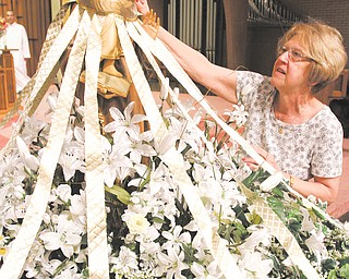 Kathy Rimedio, a member of St. Anthony of Padua Church, 1125 Turin St., Youngstown, decorates the statue of the patron saint with white and gold roses. A Feast Day Mass will take place at 6 p.m. Thursday followed by a festival with food and music. The statue will be featured in an outdoor procession at the event.