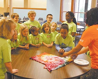 Kristie Gearhart, right, assistant director at the art camp, gets the attention of participants as she shows the result of the tie-dye T-shirt project. Children will wear the shirts during the week.