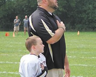 THE WINNING PICTURE CAPTURES PATRIOTIC PARTNERS!
Jim Morgan of Liberty helps coach his son Michael’s Liberty Little Leopards football team.
In this picture they are shown before a game as the National Anthem is being played.
As the winners of this year’s photo contest, the two guys get to share $100 in gift certificates from the Mahoning Valley Scrappers, good toward the purchase of game tickets, merchandise and food.