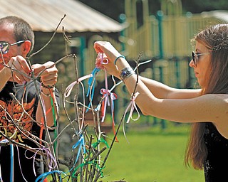 Jason Berg and Lee Sokol of the Silver Grove Society tie ribbons to the ceremonial tree to symbolize things they need during a midsummer ritual at Girard-Liberty Memorial Park. The society is an eclectic pagan community group.
