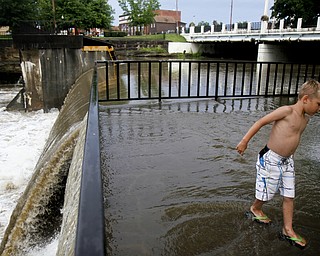 MADELYN P. HASTINGS I THE VINDICATOR
Caiden Miller, 6, of Newton Falls plays in the overflow of the river near the dam by Veteran's Park in Newton Falls over the west branch of the Mahoning River after a storm on July 10, 2013.