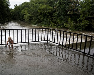 MADELYN P. HASTINGS I THE VINDICATOR
Caiden Miller, 6, of Newton Falls plays in the overflow of the river near the dam by Veteran's Park in Newton Falls over the west branch of the Mahoning River after a storm on July 10, 2013.