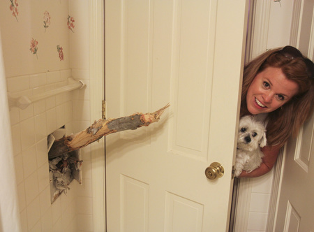 William D Lewis The Vindicator MAry Baumeier looks a tree limb that broke through  the 2nd floor wall of her Ravine Drive home in Liberty Wed during heavy storms. A large oak tree fell and partially landed on her house. no one was injured. Her dog's name is Odie.