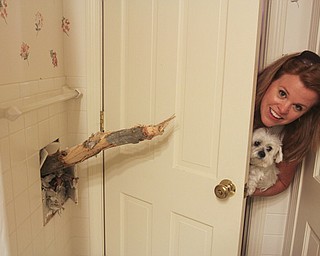William D Lewis The Vindicator MAry Baumeier looks a tree limb that broke through the 2nd floor wall of her Ravine Drive home in Liberty Wed during heavy storms. A large oak tree fell and partially landed on her house. no one was injured. Her dog's name is Odie.