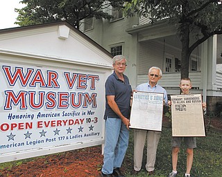 From left, Doug Speece, Frank Micchia and Joseph Conroy III stand outside of the War Vet Museum in Canfield. Speece accepted Micchia’s donated World War I and World War II editions of The Vindicator on behalf of his father, Lewis Speece, who owns the museum.