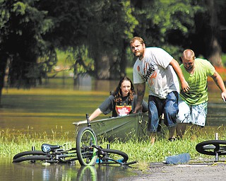 From left, Shelby Bosley, Jeff Reider and Jake Henry of Leavittsburg pull their canoe to dry land on Meadowbrook
Drive on Thursday as they help evacuate residents from low-lying areas of Leavittsburg.