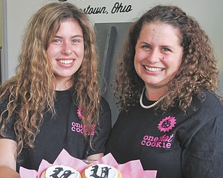 One Hot Cookie owner Bergen Giordani, right, and her daughter, Morgen Giordani, display customized cookies. Bergen opened the shop in April at 112 W. Commerce St. in Erie Terminal Square in downtown Youngstown. Morgen also works there. At top left, a sampling of cookies available at the store, which also sells locally made Katie’s Korner ice cream.