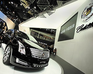 In this April 21 photo, a model poses with a Cadillac XTS displayed at the Shanghai International Automobile Industry Exhibition in Shanghai, China. General Motors’ global sales grew almost 4 percent in the first half of the year, enough to fend off Volkswagen to keep second place and perhaps bring the Detroit company closer to sales leader Toyota, according to GM on Tuesday.
